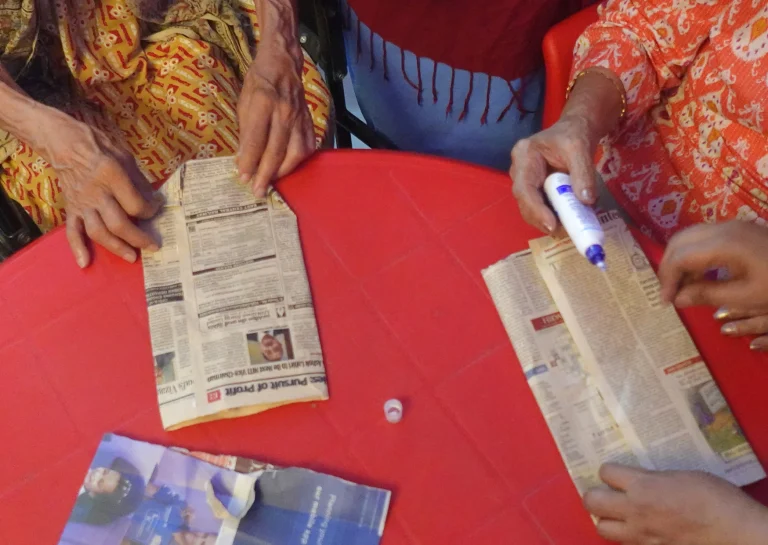 Residents taking part in a hands-on newspaper activity at Saksham by Kriti